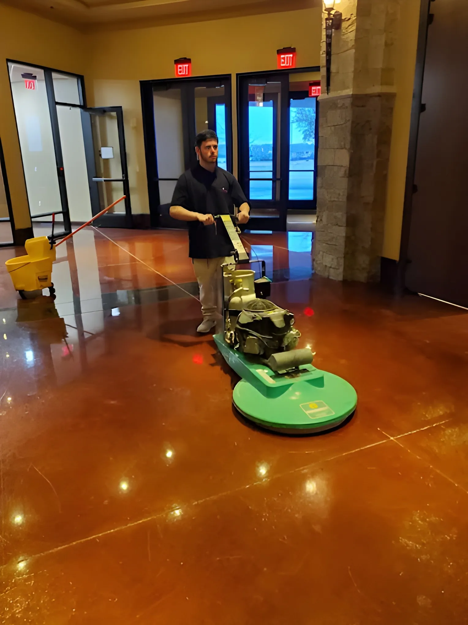 A Frisco Brothers crew member running a high-speed burnisher across a polished stained-concrete lobby floor