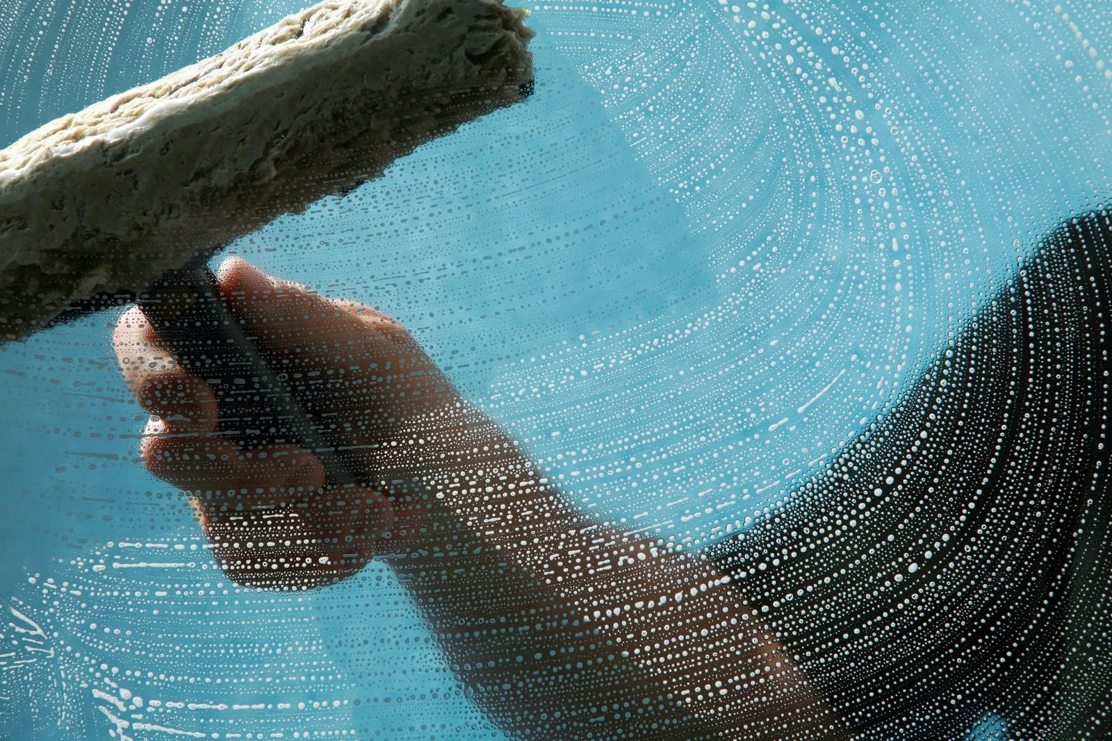 A soapy squeegee leaving a spiral wipe pattern on freshly washed glass